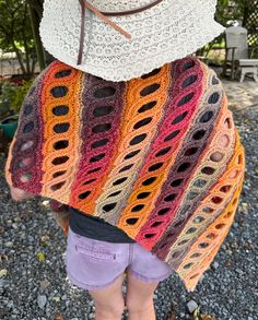 a woman wearing a crocheted shawl with a hat on top of her head