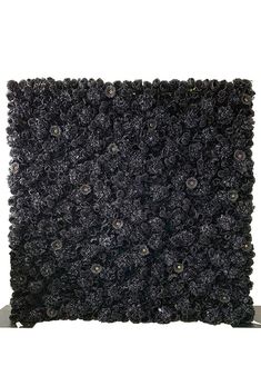 a black square shaped object with flowers on the top and bottom, sitting in front of a white background