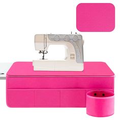 a pink sewing machine sitting on top of a table next to a cup and container