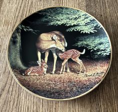 a deer and her fawn in the woods on a plate