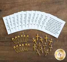 several crosses, pins and paper clips are laid out on a wooden table next to a book