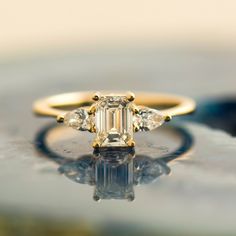 an engagement ring with three diamonds on it's side, sitting on a surface