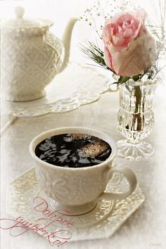 a cup of coffee on a saucer next to a vase with flowers in it