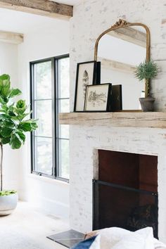 a living room with a white brick fireplace and potted plant on the mantel