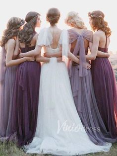 a group of women standing next to each other in long purple dresses and veils