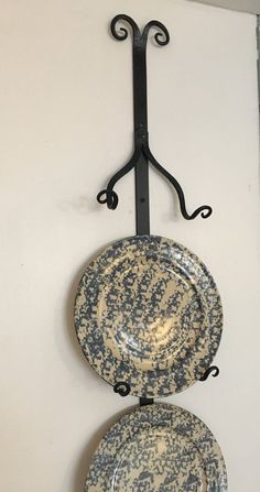 two plates are hanging on the wall next to each other and one has a black metal hook