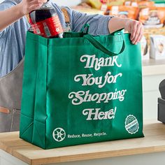 a woman holding a green shopping bag with the words thank you for shopping held on it