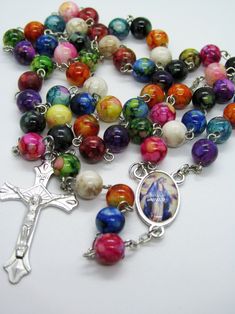 This 5 decade traditional rosary is made with mixed colors and designs of Plastic beads. The beads are 8mm. The cross / crucifix is a corpus cross and the center is a beautiful picture of Our Lady, Queen of Peace. This rosary is lightweight and very colorful. I think kids would really like it and I hope you enjoy it too. I hope you enjoy the rosary! Rosary are great Mother's Day, Birthday and Christmas gifts as well as First Communion and Baptisms.. Note: Colors may vary depending upon screen re Multicolor Rosary Bracelet With 8mm Beads As Gift, Multicolor 8mm Beads Rosary Bracelet As Gift, Multicolor 8mm Bead Rosary Bracelet Gift, Multicolor Spiritual Rosary Bracelet With 8mm Beads, Multicolor Beaded Rosary As Gift, Spiritual Multicolor Rosary Bracelet With Colorful Beads, Multicolor Rosary With 8mm Beads As Gift, Multicolor 8mm Beads Rosary As Gift, Our Lady Queen Of Peace