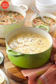 three bowls of soup sitting on top of a wooden table next to plates and utensils