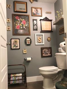 a white toilet sitting in a bathroom next to a wall covered with pictures and frames