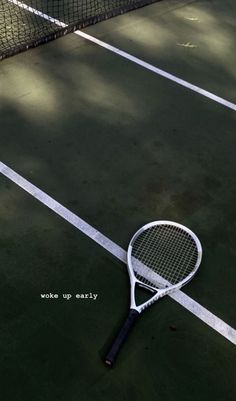 a tennis racquet laying on the ground next to a net with words written on it