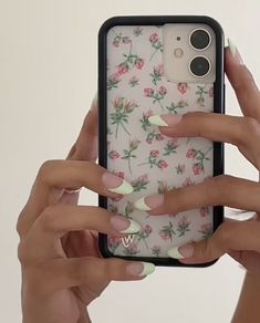 a woman holding up her phone case with flowers on it