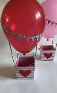 three balloons in boxes with flags and hearts on them