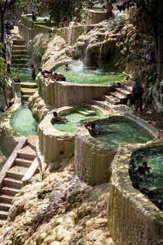 several people are swimming in the water at an outdoor hot springs area with stairs leading up to them