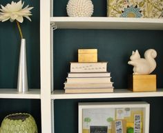 the bookshelves are filled with different types of items and flowers in vases