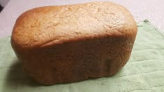 a loaf of bread sitting on top of a green towel next to a white counter