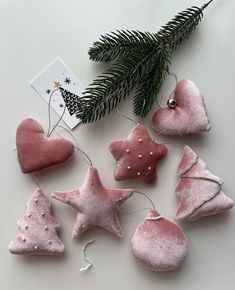 pink ornaments are hanging from a tree branch on a white surface with a christmas card in the background