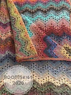 a multicolored crocheted blanket sitting on top of a bed