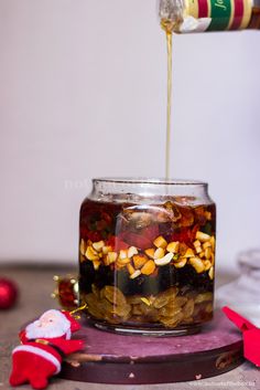 a jar filled with food sitting on top of a wooden table next to a christmas decoration