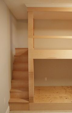 there is a bunk bed in the corner of this room with stairs leading up to it