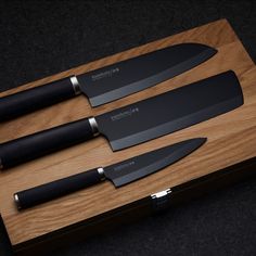 three knives are sitting on a wooden cutting board