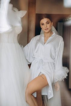 Make your wedding day morning even more special with our short silk wedding robe with feathers. Crafted from high-quality silk, this luxurious bridal robe is designed to make every bride feel elegant and comfortable as she prepares for her big day. The delicate feathers adorning the cuffs add a touch of glamour and uniqueness, making it a stunning choice for your wedding day photos.  * Length 85-90 cm / 33-35 in * Handmade * High-quality soft Armani silk * Made to measure * Feathers on buttons ( Feathered Robe For Wedding Night, Elegant Robe With Feather Trim For Wedding Night, Elegant Wedding Robe With Feathers, Wedding Satin Robe With Feathers, Elegant Satin Robe With Feathers, Satin Wedding Dress With Feather Trim, Wedding Satin Dress With Feather Trim, Elegant Satin Dresses For Bachelorette Party, Elegant Satin Robe For Honeymoon