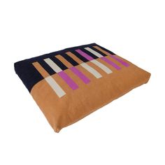 an orange and black pillow with purple stripes on the front, sitting against a white background