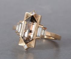 Named after Hilma AF Klint. This new setting was a dream ring we had been envisioning in the back of our minds for some time. For our first ring we chose this lovely 1.74ct Champagne Rosecut Elongated Hexagon Diamond and we accented it with some good size diamond baguettes and a few princess diamonds on the top and b Unique Witchy Engagement Rings, Saphire Engament Ring Bezel, Art Deco Fine Jewelry, Art Deco Ring Vintage, Architectural Engagement Ring, Gold And Black Engagement Ring, Artemer Engagement Rings, Elongated Hexagon Ring, Weird Wedding Rings