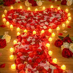 many lit candles are arranged in the shape of a heart and surrounded by rose petals