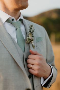 a man wearing a suit and tie with a boutonniere on his lapel