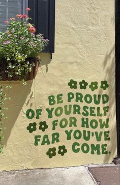 a potted plant sitting on the side of a building next to a sign that says be proud of yourself for how far you've come