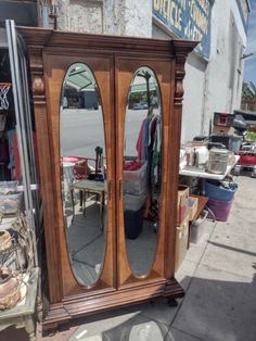 a wooden armoire sitting on the side of a road next to a store front