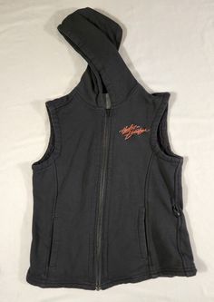 Harley Davidson women's sleeveless hooded full zip vest, size small. This vest is pre-owned. Please see pictures for approximate measurements. Feel free to reach out with any questions. Black Sleeveless Cotton Outerwear, Fitted Black Hooded Vest, Black Fitted Hooded Vest, Black Sleeveless Vest For Outdoors, Black Hooded Vest For Streetwear, Sporty Stretch Hooded Vest, Stretch Sleeveless Vest For Outdoor, Casual Hooded Tank Top For Sports, Black Cotton Vest For Winter