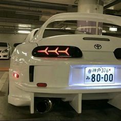 the back end of a white car in a parking garage