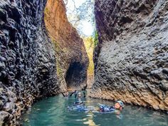 people swimming in the water between two large rocks on either side of a narrow river