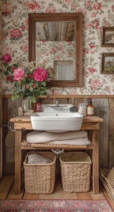 a white sink sitting under a mirror next to a wooden table with baskets on it