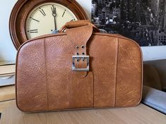 "Vintage circa 1970s Woolworth small suitcase/ luggage / carryon bag. Faux leather tan/brown color.  Measures approximately 22\" x 13.5\" x 10\".   Please note this is a vintage item and does show signs of wear.   Most notable is that three out of four of the pegs on the bottom of the bag are missing. There is also some discoloration on the inside of the suitcase as well as some scuff marks on the outside. Please see photos.  The zippers are working smoothly. There is no key." Vintage Brown Travel Bag With Luggage Sleeve, Vintage Cognac Briefcase For Travel, Vintage Brown Luggage For Everyday Use, Vintage Brown Satchel Travel Bag, Vintage Brown Luggage For Trips, Retro Brown Travel Briefcase, Retro Brown Briefcase For Travel, Retro Brown Briefcase, Carryon Bag