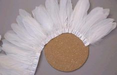 a white feather headdress with a cork circle on it's center piece