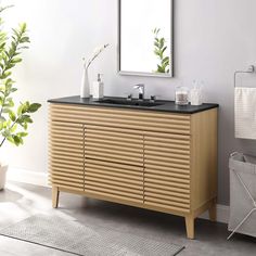 a bathroom with a sink, mirror and plants in the corner on the wall next to it