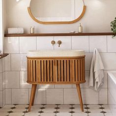 a bathroom with white tile and wood accents, including a wooden sink cabinet in the center