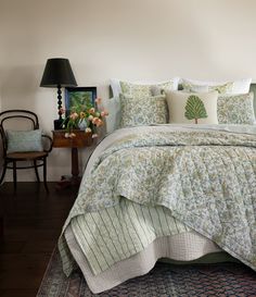 a bed with green and white bedspread in a bedroom next to a lamp