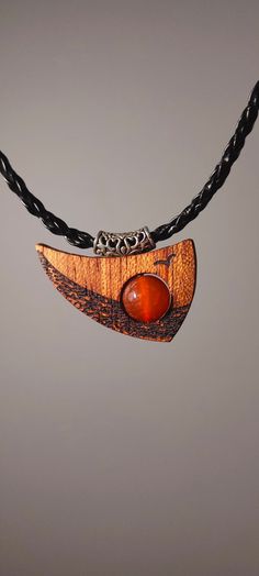 "Surprise your friend or enrich your outfit with unique handmade wooden necklace with a gemstone. It is made of African Bodo wood and charming Agate Stone. Buying this wooden pendant you will get a stone-talisman of strength and wellbeing for all the life. Sunset Ocean inspiration is what our Sunset Ocean pendant symbolises. This unique bodo wood pendant with its unusual shape immerses you in a world of nautical adventure and endless horizons. The agate stone in the center of the pendant, which rotates around its axis, represents the sun at sunset. Agate symbolises strength, harmony and poise, while the bodo tree symbolises resilience and the natural beauty of nature.  PENDANT SIZE:  26*36mm  NECKLACE LENGTH: 45 cm the width 3 mm \"Sunset Ocean\" is not just a piece of jewellery - it is a Artisan Necklace In Natural Wood As A Gift, Artisan Necklaces In Natural Wood As Gift, Handmade Wooden Necklace Gift, Brown Carved Round Pendant Necklace, Adjustable Natural Wood Pendant Jewelry, Carved Orange Jewelry For Gifts, Gift Wooden Bead Necklaces In Natural Wood, Carved Orange Jewelry For Gift, Natural Wood Necklaces With Wooden Beads For Gift