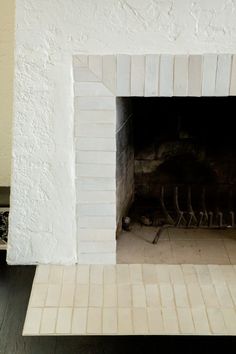 a fire place in the middle of a room with tile flooring and white walls