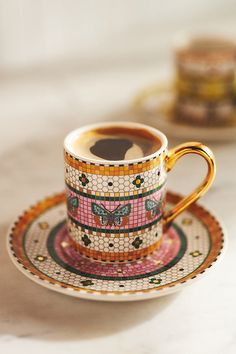 there is a cup and saucer on the table next to each other with different designs