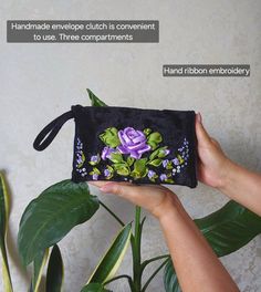 a hand holding a black purse with purple flowers on it and the words handmade envelope clutch is convenient to use