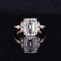 an emerald cut diamond ring with diamonds surrounding it