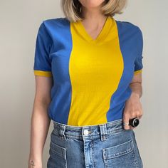 1970s Blue and Yellow Retro T Shirt/Vintage Cotton Sports T Shirt/ 70s Unisex V-Neck T Shirt  Made in France. 100% Cotton.  Pit to Pit: 32" (16" Laid Flat) - does have a slight stretch Shoulder to Shoulder: 16" Collar to Hem (on back of item): 27" Would fit approx size - UK 8/10 FR 36/38 US 4/6 Model is a UK 10/34DD Bust for size reference.  Condition - Great Vintage Condition. Slight Pilling to fabric but not noticeable. We do not offer exchanges or returns on our clothing, please inspect the photos carefully and feel free to ask any questions. Jx Retro V-neck T-shirt For Summer, Fitted Blue Color Block T-shirt, Blue Color Block V-neck Top, Vintage Cotton V-neck Top, Retro Yellow Tops With Retro Print, Yellow Retro Tops With Retro Print, Yellow Retro Print Tops, Fitted Color Block V-neck Top, Fitted V-neck Color Block Top