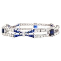 Indulge in the timeless allure of Art Deco with our stunning Blue Sapphire and Diamond Bracelet set in platinum. This exquisite piece embodies the essence of Art Deco design, boasting a perfect blend of quintessential Art Deco symmetry and vibrant contrast. The captivating blue sapphires and dazzling diamonds are meticulously arranged in a symmetrical geometric pattern, echoing the era's iconic style. The focal point showcases three stunning Emerald-cut Blue Sapphires, totaling 4 carats. Complem Timeless Blue Round Bracelets, Timeless Blue Bracelet For Formal Occasions, Timeless Blue Diamond Bracelet, Luxury Blue Diamond Bracelet, Luxury Sapphire Tennis Bracelet For Formal Occasions, Luxury Sapphire Bracelet For Formal Occasions, Luxury White Gold Sapphire Diamond Bracelet, Luxury Blue Diamond Bracelet With Brilliant Cut, Luxury Sapphire Tennis Bracelet