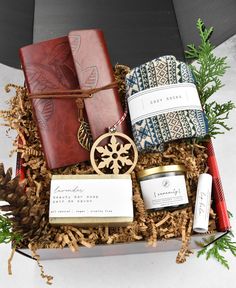 an open gift box filled with candles, books and other holiday gifts for someone special