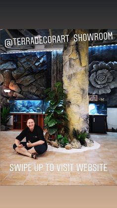 a man is sitting on the floor in front of a large tree and some plants